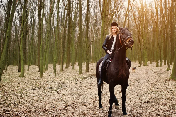 Mladé stylové Blondýnka, jízda na koních v podzimním lese. — Stock fotografie