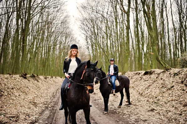 Jong stijlvolle koppel rijden op paarden op herfst bos. — Stockfoto