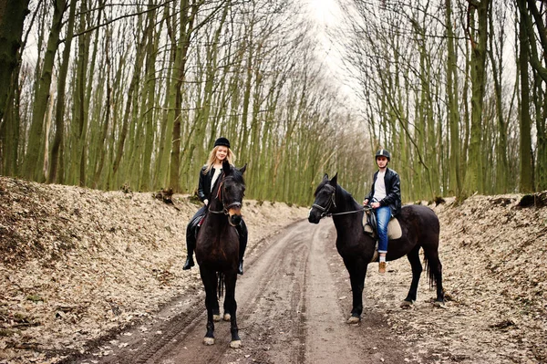 Jong stijlvolle koppel rijden op paarden op herfst bos. — Stockfoto