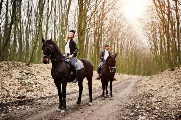 Jovem casal elegante montando em cavalos na floresta de outono . — Fotografia de Stock