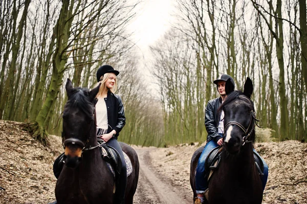 Jong stijlvolle koppel rijden op paarden op herfst bos. — Stockfoto