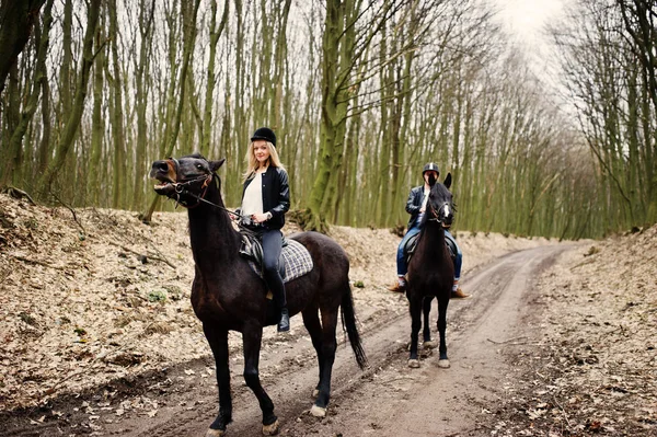 Jovem casal elegante montando em cavalos na floresta de outono . — Fotografia de Stock