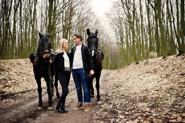 Jonge stijlvolle paar verliefd in de buurt van paarden op herfst bos. — Stockfoto