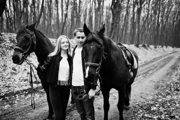 Jonge stijlvolle verliefde paar in de buurt van paarden op herfst bos. Zwart — Stockfoto