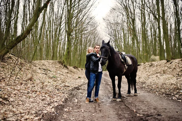 Joven pareja con estilo en el amor cerca de caballo en el bosque de otoño . — Foto de Stock