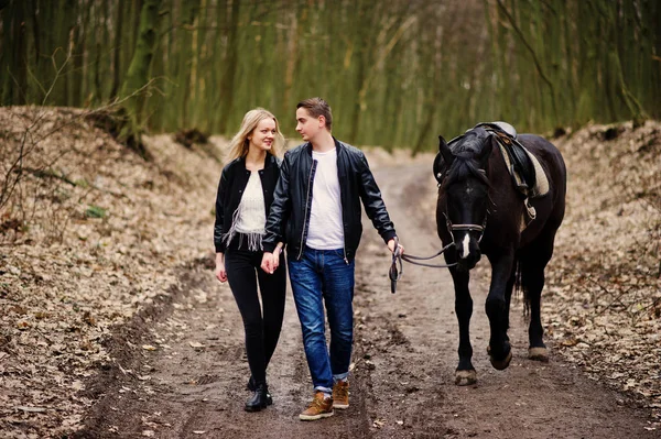 Young stylish couple in love walking with horse at autumn forest — Stock Photo, Image