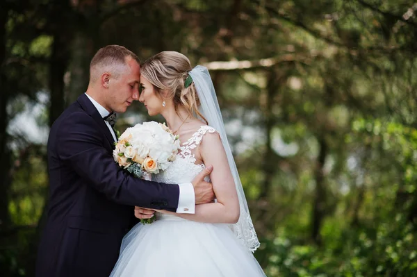 Casal de casamento na moda abraçando na floresta no casamento ensolarado da — Fotografia de Stock