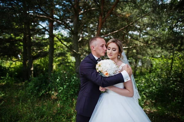 Fashionable wedding couple hugging at forest on sunny wedding da — Stock Photo, Image