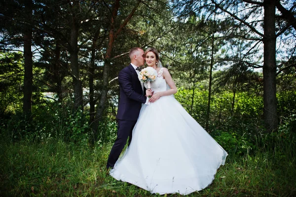 Модная свадебная пара обнимается в лесу на солнечной свадьбе — стоковое фото