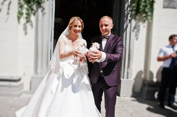 Hochzeitspaar mit Tauben an der Hand gegen Kirchentor. — Stockfoto