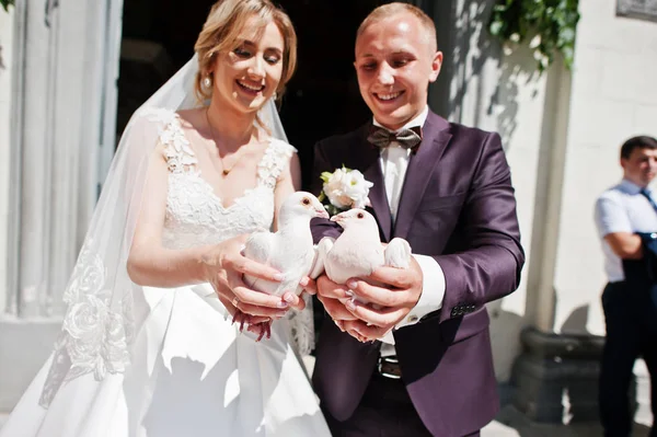 Γαμήλιο ζεύγος περιστέρια σε χέρια έναντι εκκλησίας πύλη. — Φωτογραφία Αρχείου