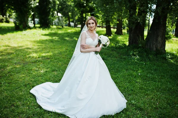 Noiva loira bonito com buquê de casamento no parque no dia ensolarado . — Fotografia de Stock