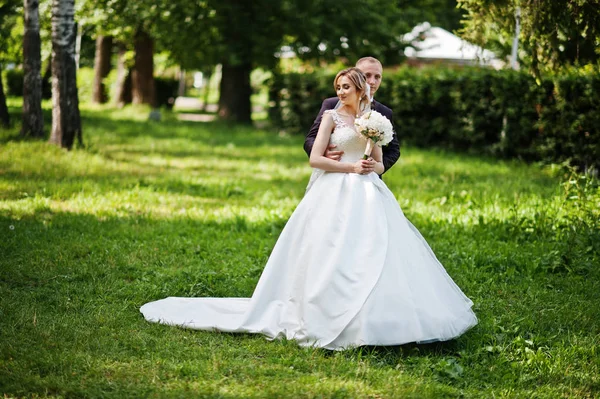 Модная свадебная пара обнимается в зеленом парке на солнечной свадьбе — стоковое фото