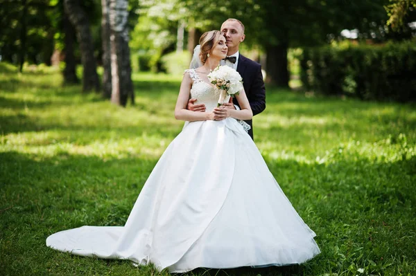 Casal de casamento na moda abraçando no parque verde no casamento ensolarado — Fotografia de Stock