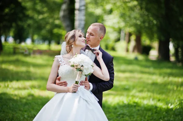 Abbracci di coppia nuziali alla moda a parco verde su matrimonio soleggiato — Foto Stock