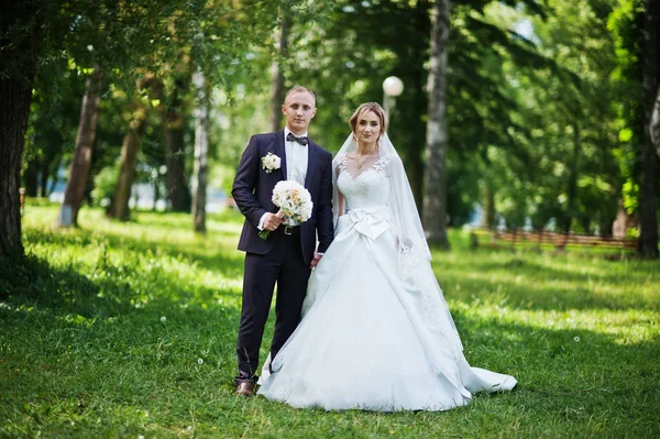 Couple de mariage à la mode étreignant au parc vert sur weddin ensoleillé — Photo