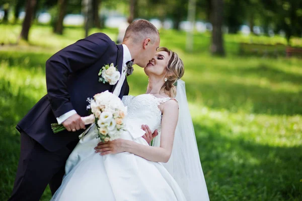 Şık düğün çift sunn üzerinde yeşil park sarılma öpüşme — Stok fotoğraf