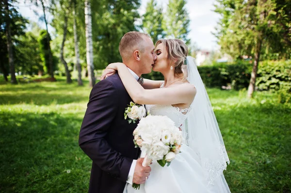 Fashionable kissing wedding couple hugging at green park on sunn — Stock Photo, Image