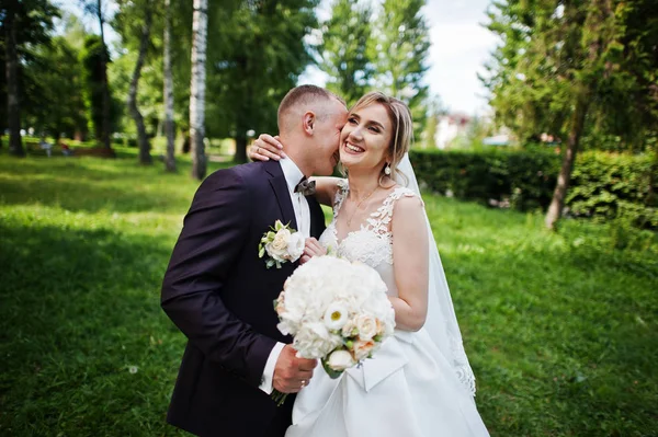 Fashionable wedding couple hugging at green park on sunny weddin — Stock Photo, Image