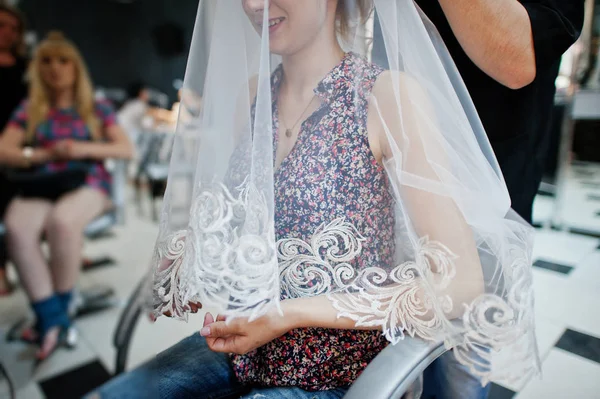 Hair stylist makes the bride a wedding hairstyle under veil at b