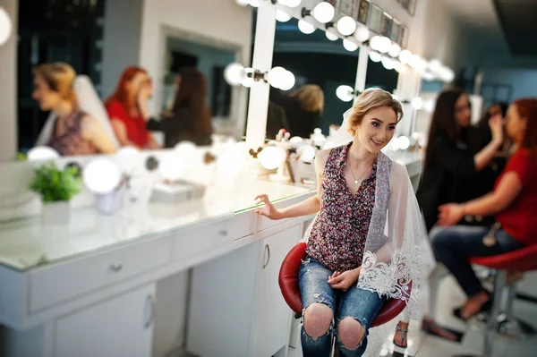 Giovane sposa ragazza seduta sulla sedia vicino specchio al salone di bellezza . — Foto Stock