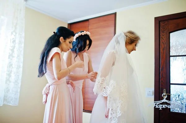 Modieuze bruidsmeisjes op roze jurken hielp slijtage strik op de rug — Stockfoto