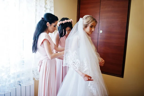 Las damas de honor a la moda en vestidos rosas ayudaron a usar lazo en la espalda —  Fotos de Stock