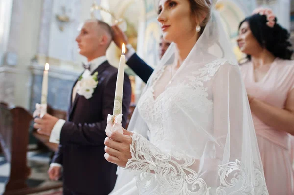 Hochzeitspaar in der Kirche mit brennenden Kerzen an den Händen. — Stockfoto