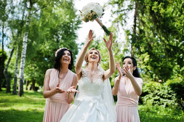 Bride posed on park with two cute brunette bridesmaids on pink d — Stock Photo, Image