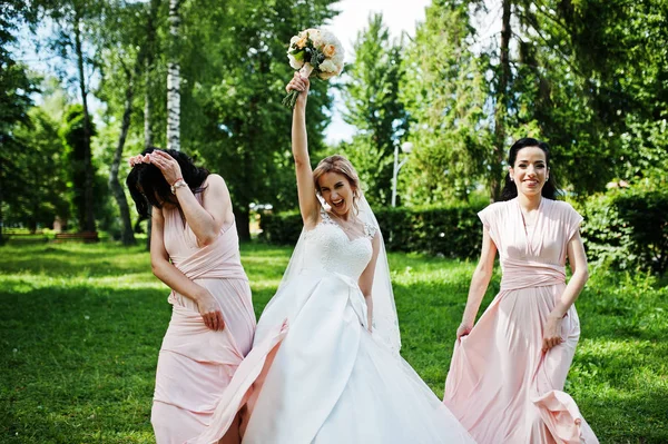 Bride posed on park with two cute brunette bridesmaids on pink d — Stock Photo, Image