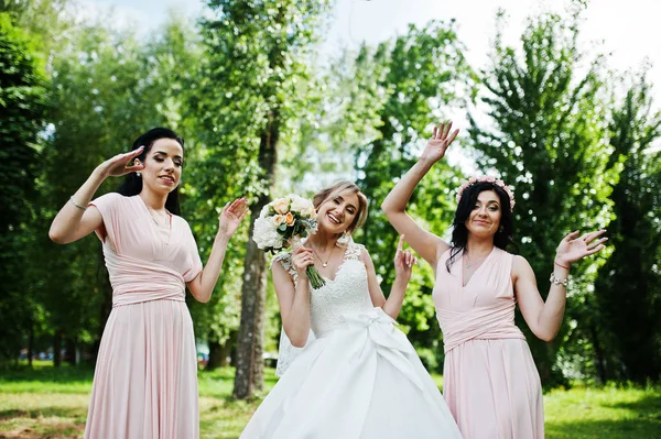 Bride posed on park with two cute brunette bridesmaids on pink d — Stock Photo, Image