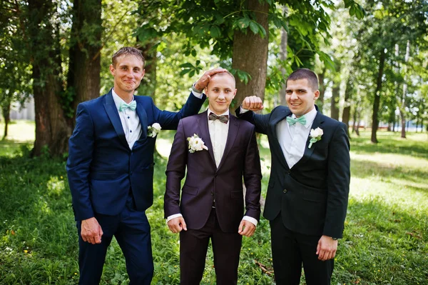 Groom with his best man\'s on wedding at park.