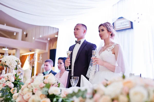 Свадебная пара с бокалами шампанского за столом в ресторане — стоковое фото