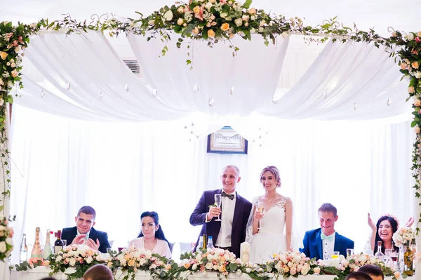 Wedding couple with champagne glasses at table on restaurant wit — Stock Photo, Image