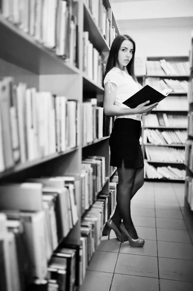 Menina morena na biblioteca com pasta de documentos, desgaste no branco — Fotografia de Stock