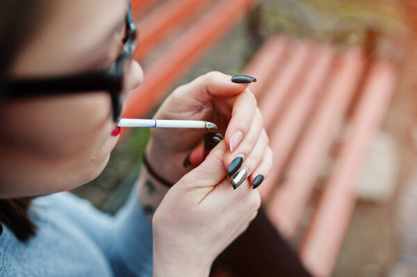 Молодая девушка, закуривающая сигарету на улице, закрывается. Понятие Нико
