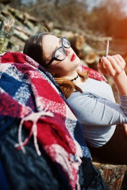 Genç kız Sigara İçilmeyen açık havada arka plan ahşap kütükler. 