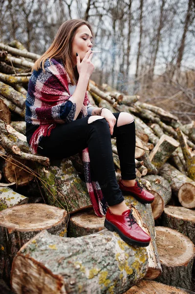 Junges Mädchen raucht Zigarette im Freien Hintergrund Holzstümpfe. — Stockfoto