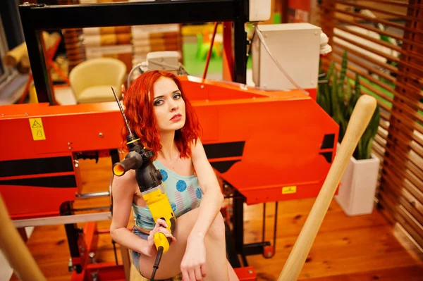 Czerwone włosy model siedzi na drewno Tartak wiertła w sklepie lub — Zdjęcie stockowe