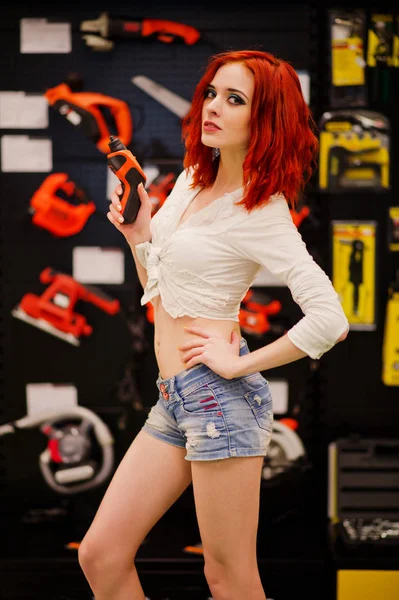 Red haired model posed with electric screwdriver at store or hou — Stock Photo, Image