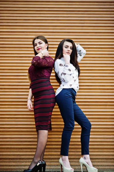 Zwei junge Teenager posierten gegen orangefarbene Verschlüsse. molliges Mädchen — Stockfoto