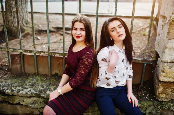 Dos jóvenes adolescentes sentadas contra una cerca de hierro. Chica regordeta v — Foto de Stock