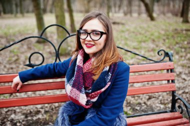 Genç hippi kız giyim ceket ve bankta oturan gözlük.