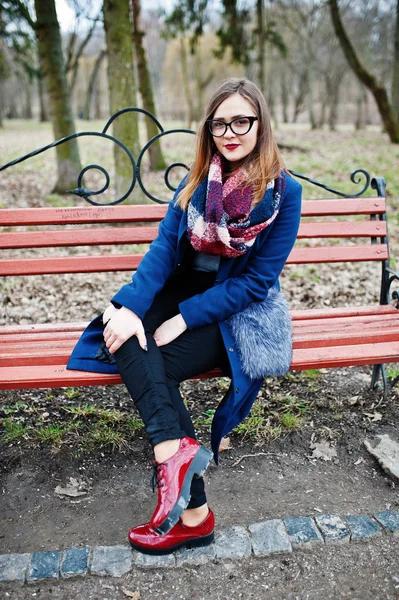 Young hipster girl wear on coat and glasses sitting on bench. — Stock Photo, Image