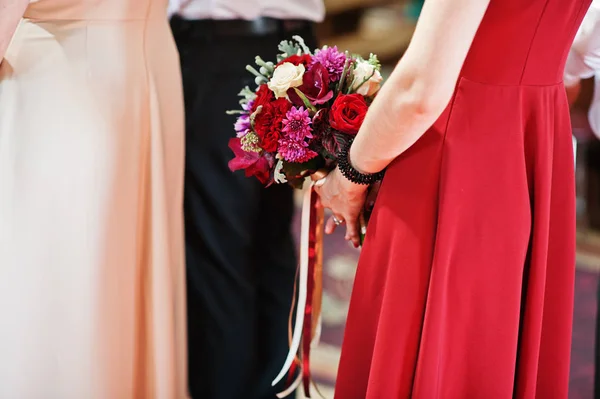 Bröllopsbuketter i händerna på bridesmaids bo på kyrklig ceremoni — Stockfoto