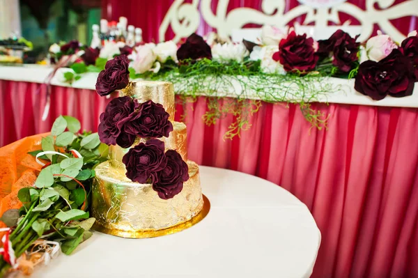 Pastel de boda de oro con deliciosas flores en la mesa pequeña . —  Fotos de Stock