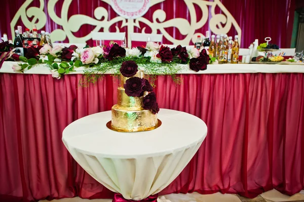 Gyllene bröllopstårta med läckra blommor vid små bord. — Stockfoto