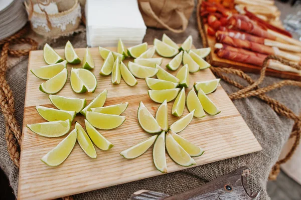 Pocięta na plasterki limonki na płyty drewna na wesele catering tabeli. — Zdjęcie stockowe