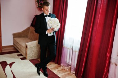 Şık Damat Düğün buket ile onun odasında eller.