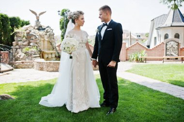 Şık Düğün çifti aşık yeşil çimenlerin üzerinde yürüyüş.